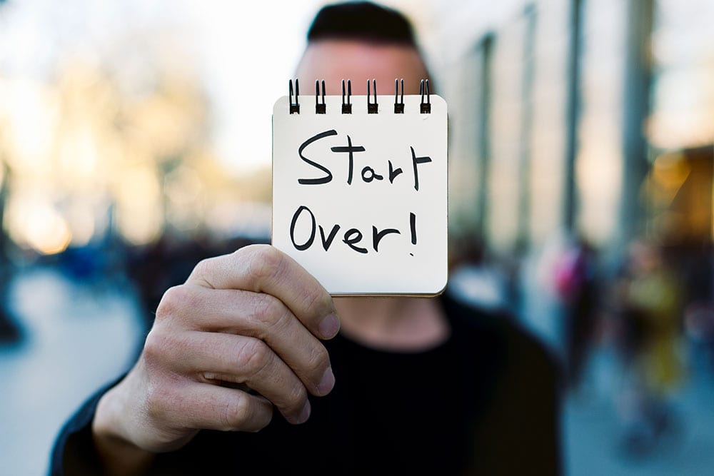photo of a man holding up the words start over, symbolic of having a criminal record cleaned to allow one to apply for work or travel again.
