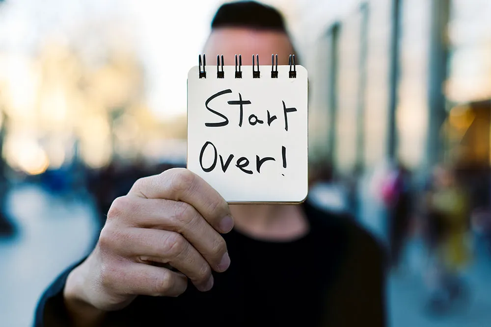 photo of a man holding up the words start over, symbolic of having a criminal record cleaned to allow one to apply for work or travel again.