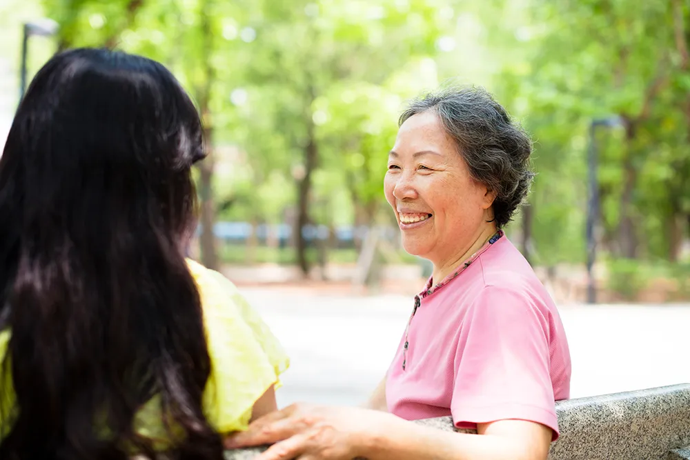 photo of a mother and daughter sitting on a park bench, the daughter is appointed as the Agent in her mother's Personal Directive which allows the Agent to provide directions on the medical care of her mother